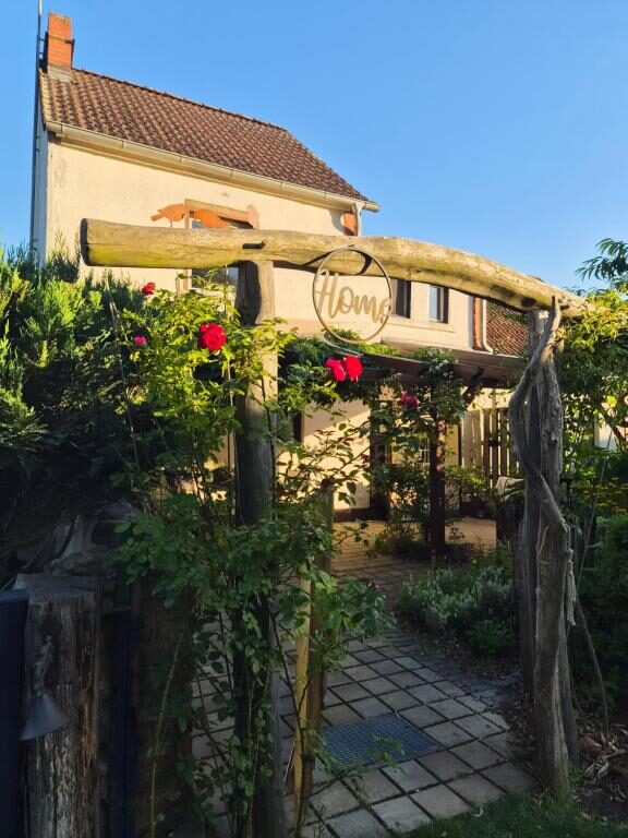 Hausansicht des Ferienhauses Cottage Eisvogel mit Eingang, Pergola und Blumen